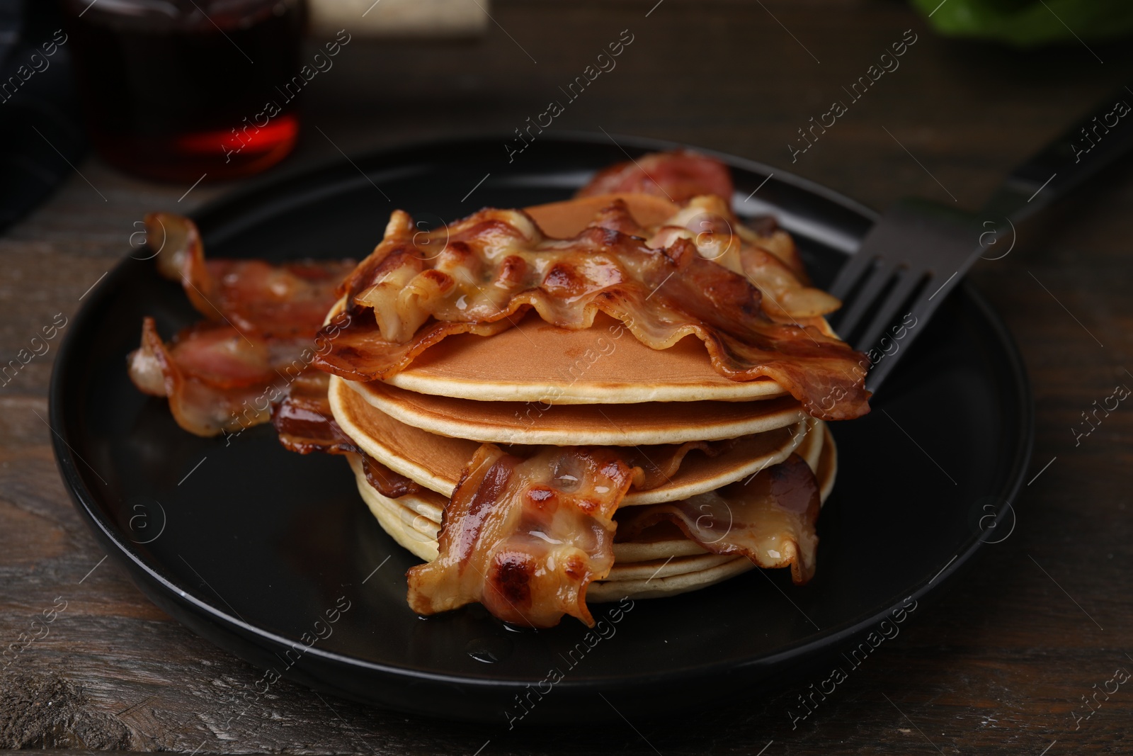 Photo of Delicious pancakes with fried bacon served on wooden table, closeup