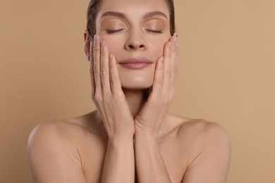 Woman massaging her face on beige background