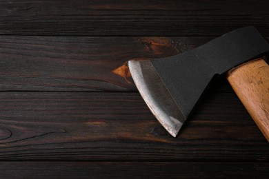 Photo of Black ax with handle on wooden table. Space for text