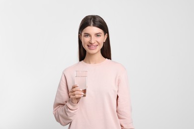 Photo of Healthy habit. Happy woman holding glass with fresh water on light grey background
