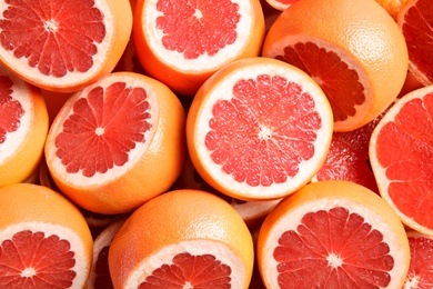 Many sliced fresh grapefruits as background, top view