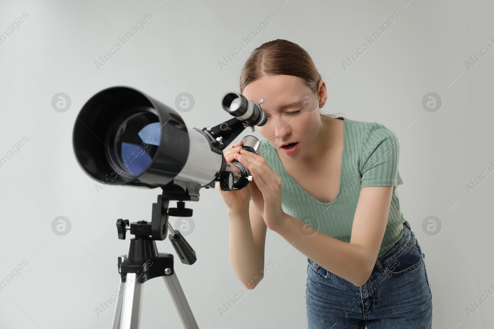 Photo of Young astronomer looking at stars through telescope on grey background