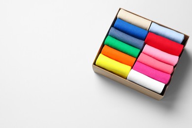 Photo of Box with different colorful socks on light background, above view. Space for text