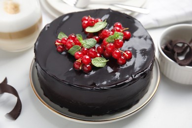 Photo of Tasty homemade chocolate cake with berries and mint on white table