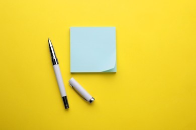 Photo of Paper note and pen on yellow background, flat lay. Space for text