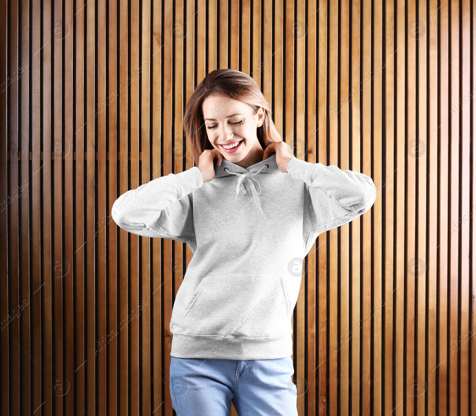 Photo of Portrait of woman in hoodie sweater on wooden background. Space for design