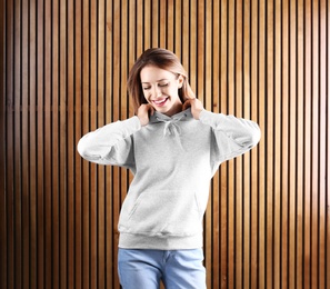 Portrait of woman in hoodie sweater on wooden background. Space for design