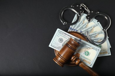 Photo of Law gavel, dollars and handcuffs on grey table, flat lay. Space for text