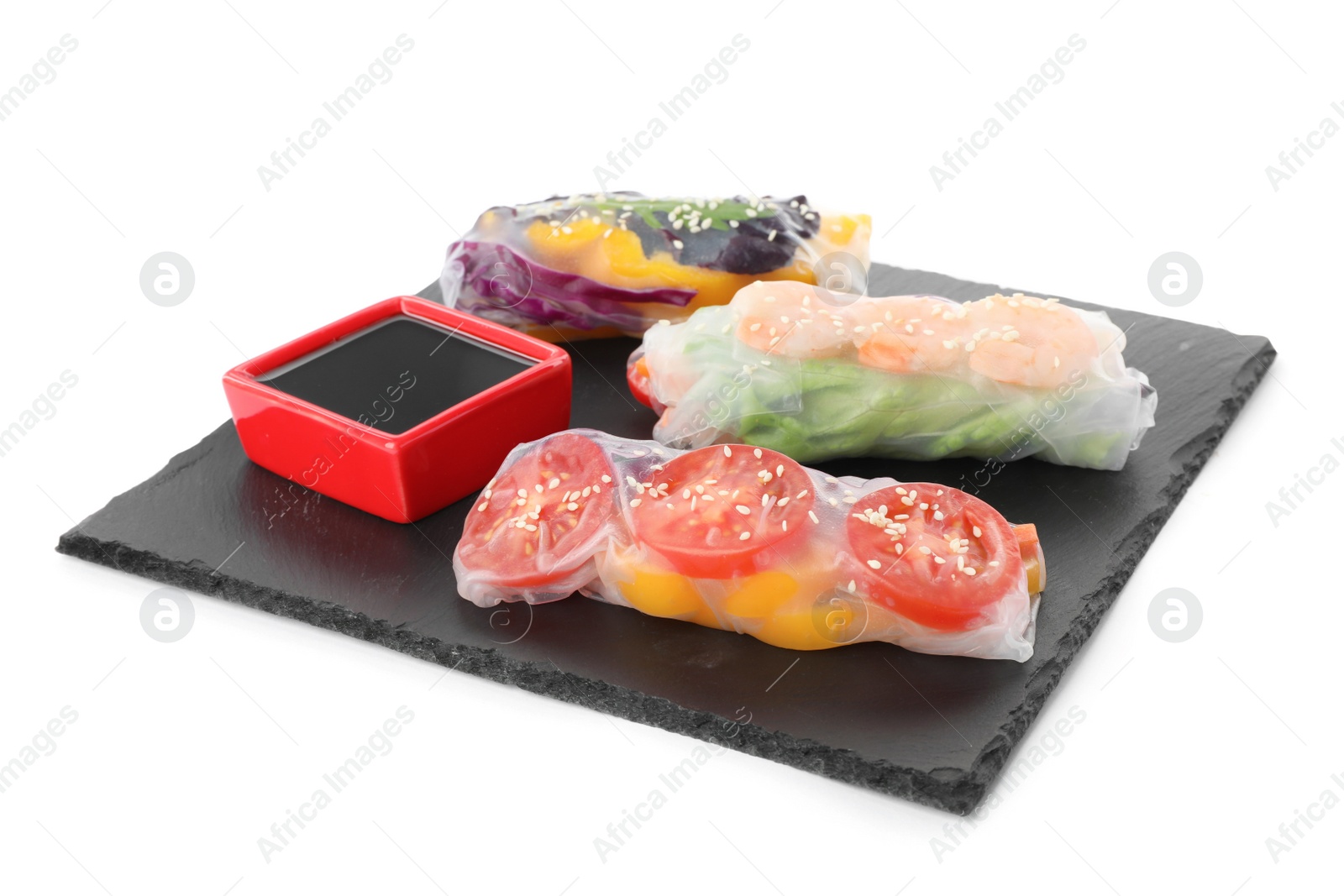 Photo of Slate plate with delicious rolls wrapped in rice paper and soy sauce on white background