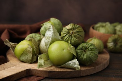 Photo of Fresh green tomatillos with husk on wooden table, closeup