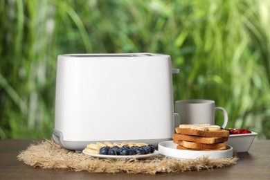 Photo of Toaster and tasty breakfast on wooden table