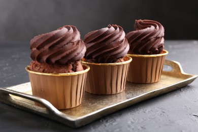 Photo of Delicious chocolate cupcakes on black textured table, closeup