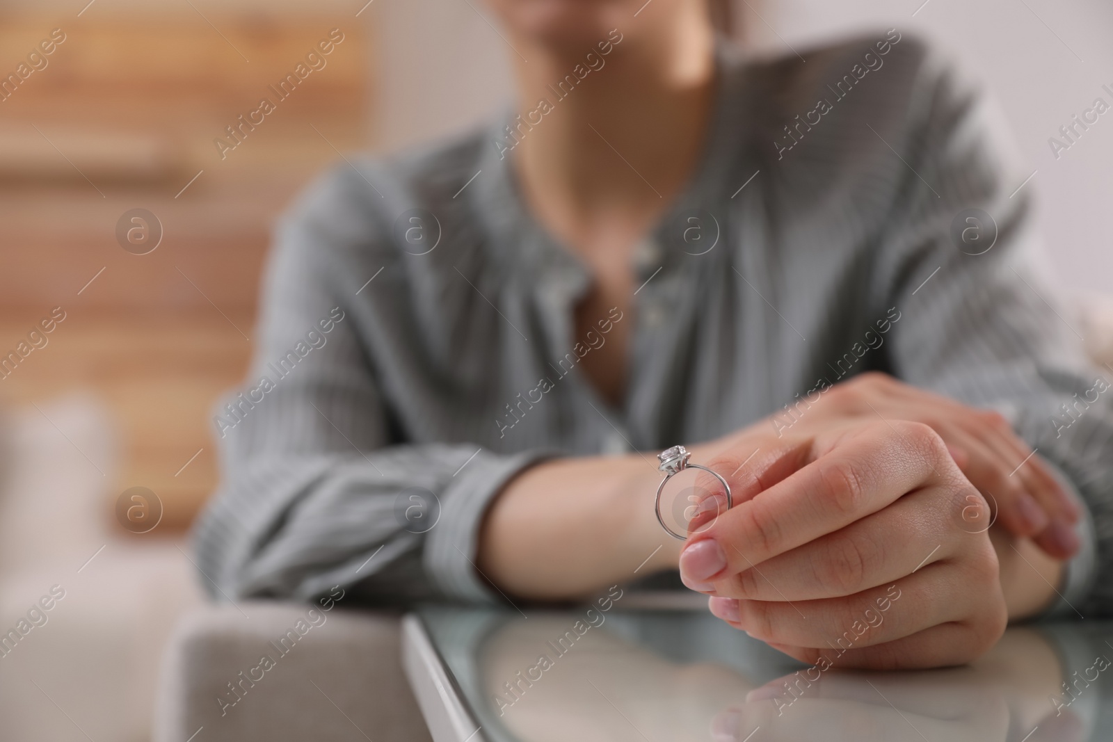 Photo of Woman holding wedding ring at table indoors, space for text. Divorce concept