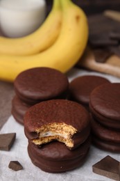 Photo of Tasty banana choco pies and pieces of chocolate on parchment paper