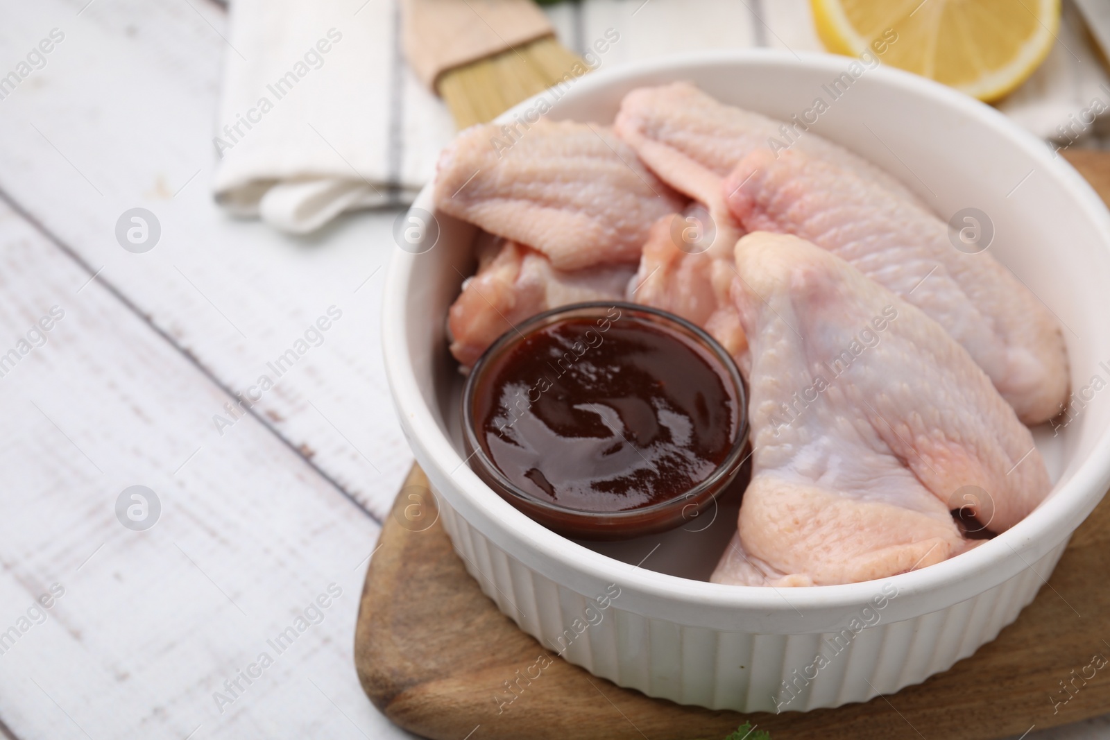 Photo of Fresh marinade and raw chicken wings on rustic wooden table, closeup. Space for text