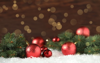 Image of Beautiful red Christmas balls and fir tree branches on snow, bokeh effect
