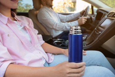 Photo of Woman with thermos on passenger seat of car, closeup
