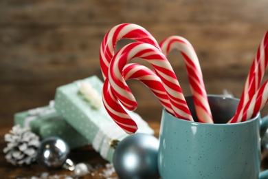 Photo of Many sweet candy canes in cup on wooden background, closeup. Traditional Christmas treat