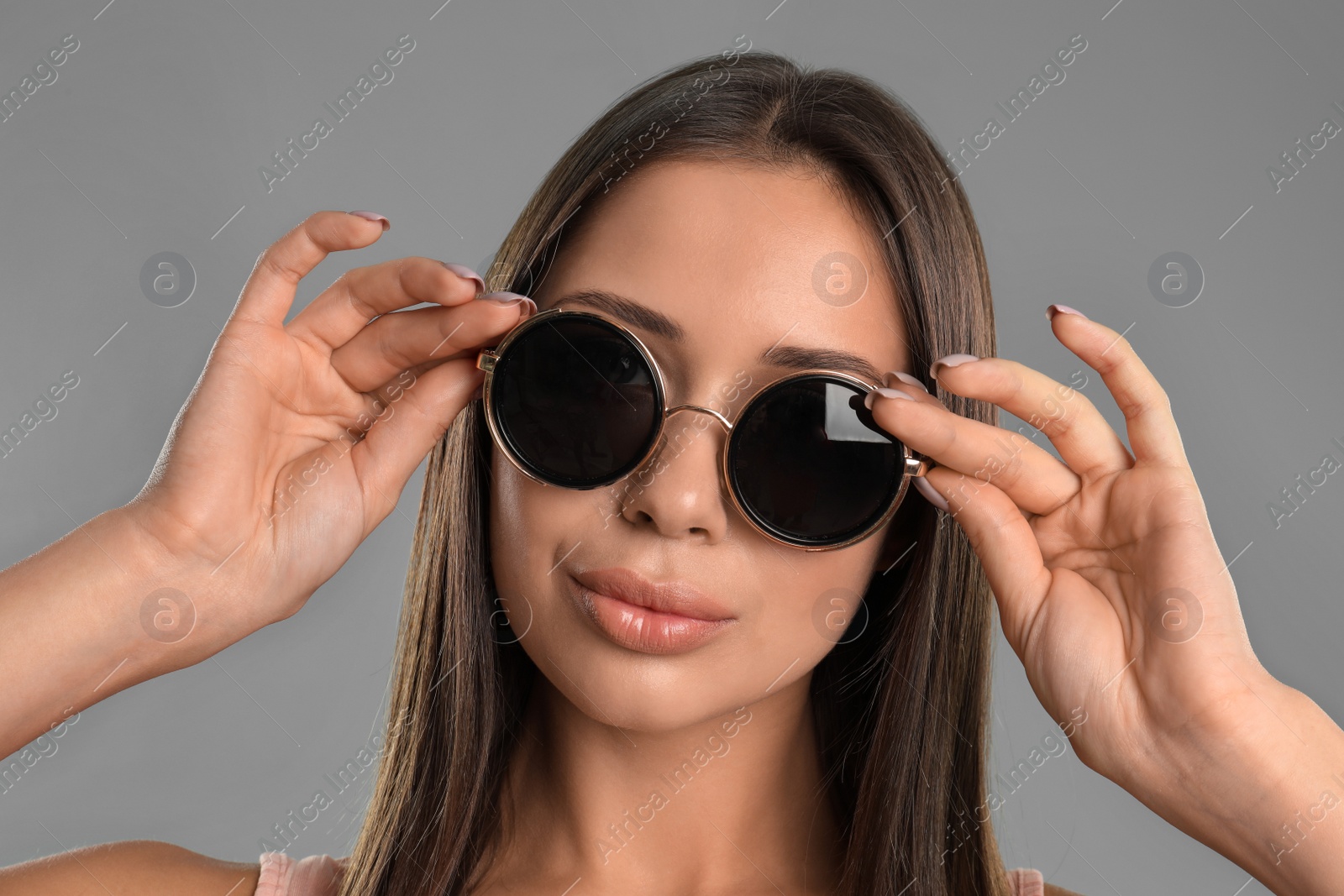 Photo of Beautiful young woman wearing sunglasses on grey background, closeup