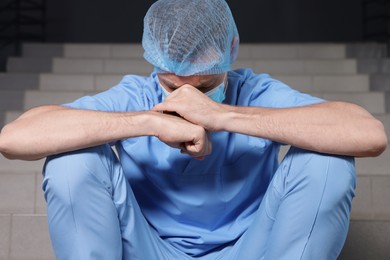 Photo of Exhausted doctor sitting on stairs in hospital