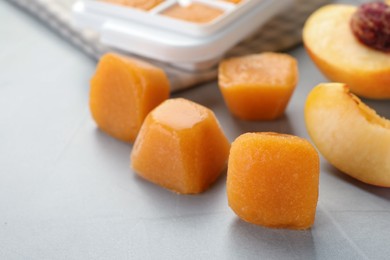 Frozen nectarine puree cubes and ingredient on light grey table, closeup