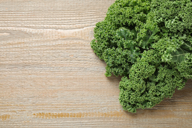 Fresh kale leaves on wooden table, top view. Space for text