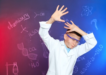 Emotional pupil shielding himself against blackboard with written chemistry formulas. Space for text