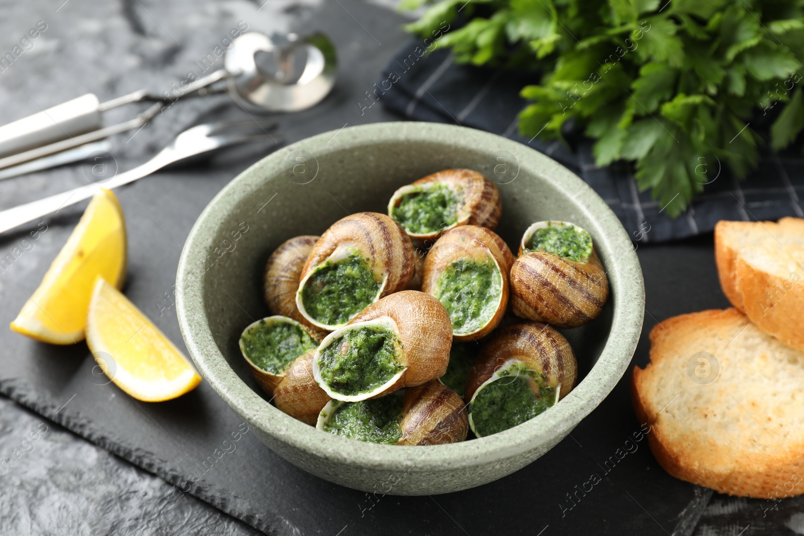 Photo of Delicious cooked snails served on grey table, closeup