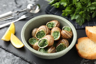 Photo of Delicious cooked snails served on grey table, closeup