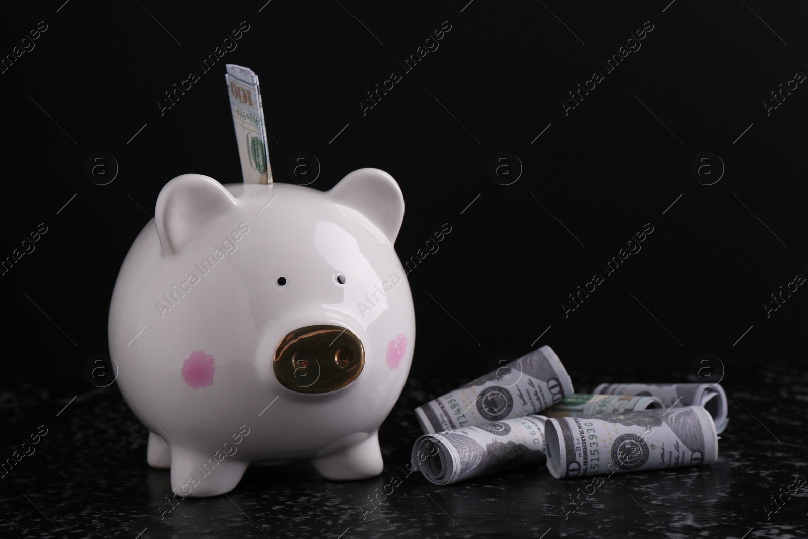 Photo of Financial savings. Piggy bank and dollar banknotes on black textured table