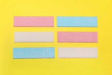 Sticks of tasty chewing gum on yellow background, flat lay