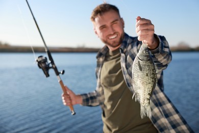 Photo of Fisherman with fishing rod at riverside, focus on catch