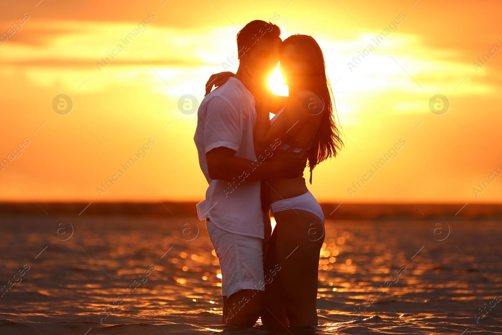 Photo of Happy young couple spending time together on sea beach at sunset