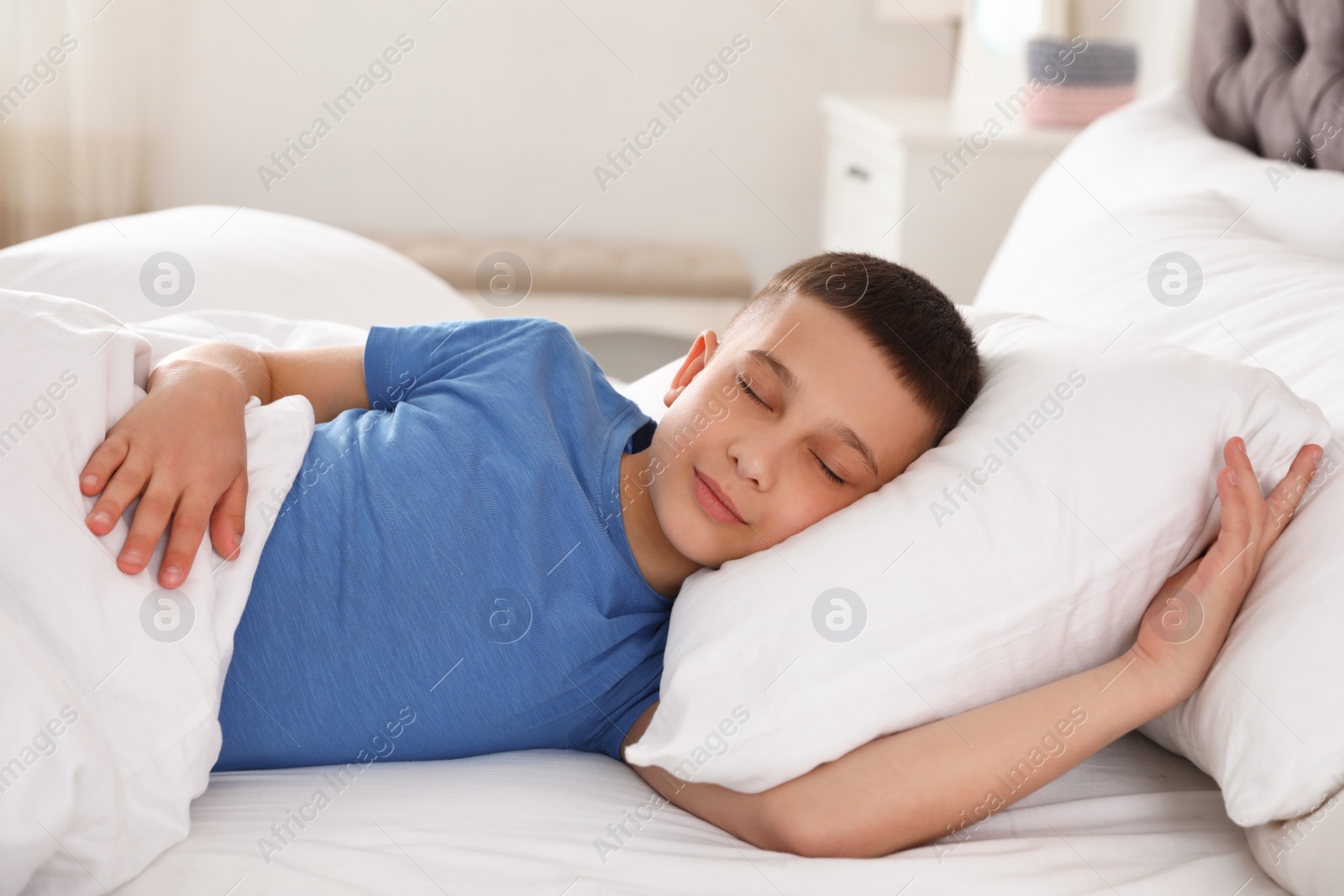 Photo of Portrait of cute boy sleeping in large bed