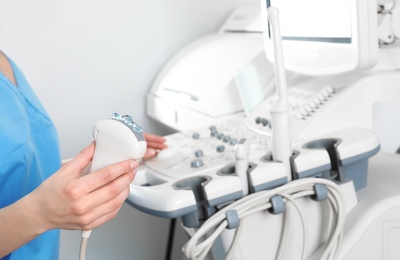 Photo of Professional sonographer using modern ultrasound machine in clinic, closeup