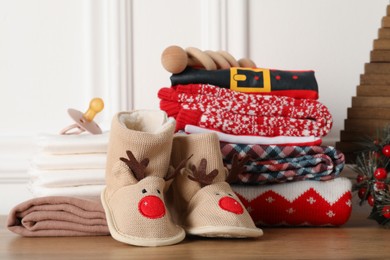 Photo of Baby clothes, accessories and Christmas decor on wooden table