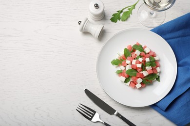 Photo of Delicious salad with watermelon, arugula and feta cheese served on white wooden table, flat lay. Space for text