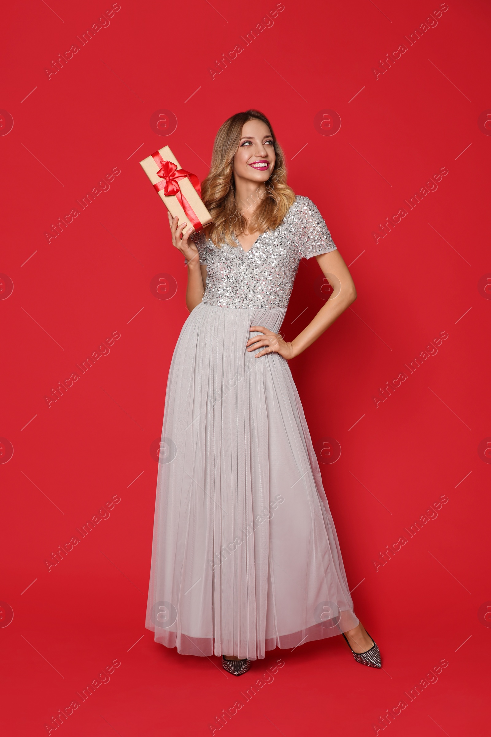 Photo of Happy woman with gift box on red background. Christmas party