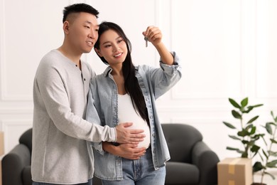 Photo of Pregnant woman and her husband with key in their new apartment, space for text