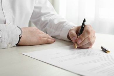 Photo of Notary signing document at wooden table, closeup