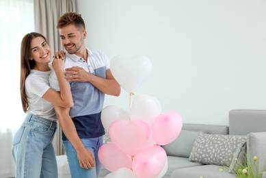 Photo of Young couple with air balloons at home. Celebration of Saint Valentine's Day