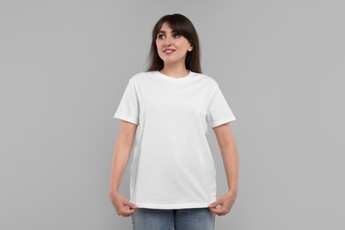 Photo of Smiling woman in white t-shirt on grey background