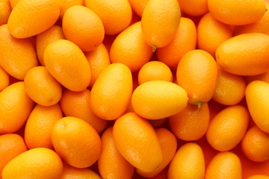 Photo of Many fresh ripe kumquats on orange background, top view