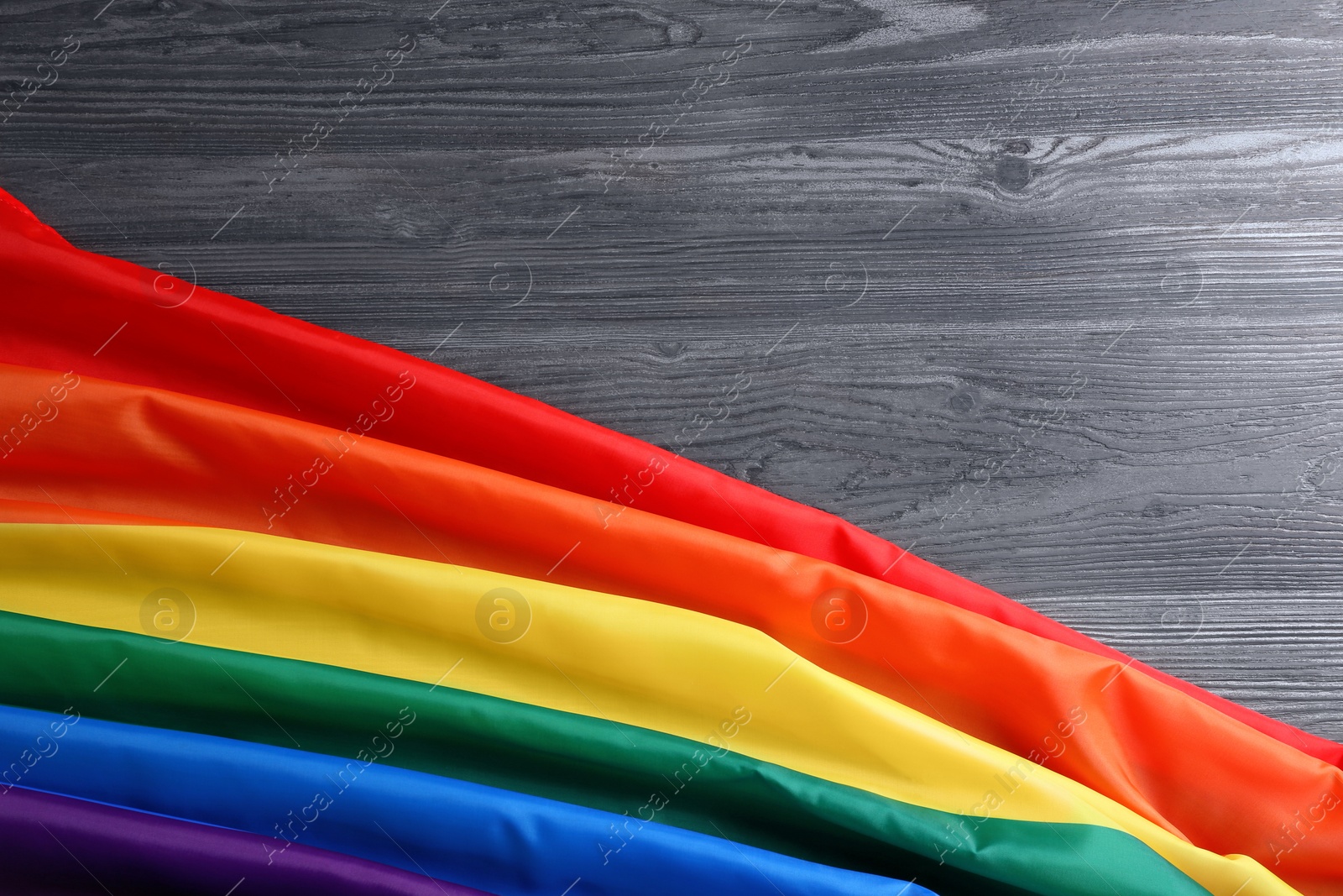 Photo of Bright rainbow gay flag on wooden background, top view with space for text. LGBT community