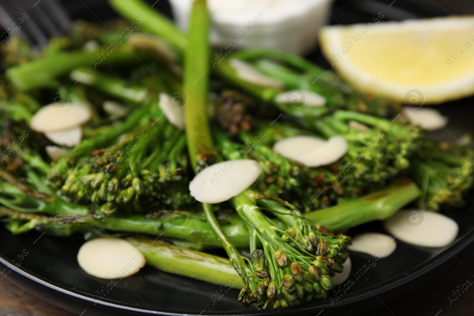 Photo of Tasty cooked broccolini with almonds on plate, closeup