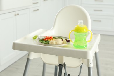Baby high chair with healthy food and water indoors