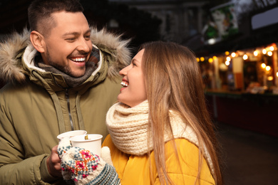 Happy couple with mulled wine at winter fair