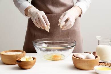 Photo of Woman preparing batter for crepes at white wooden table, closeup