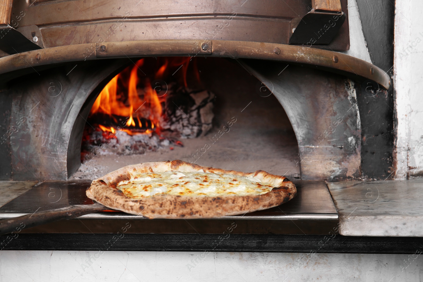 Photo of Oven with burning firewood and tasty pizza in restaurant kitchen