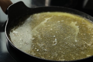 Photo of Melted butter in frying pan on table, closeup